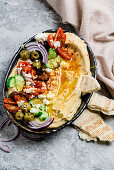 Loaded hummus platter with feta, tomatoes, cucumber, olives and onions