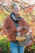 Frau mit Picknickkorb unter Zierapfelbaum im Herbstgarten