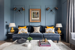 Classic living room with blue walls, color-matching velvet sofa and yellow accents