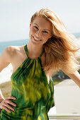 Blonde Frau in grünem Neckholder-Kleid am Meer