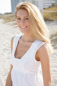 Blonde woman in white summer dress on the beach