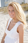 Blonde woman in white summer dress on the beach