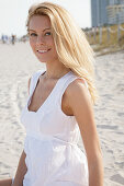 Blonde woman in white summer dress on the beach