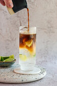 Pouring Espresso over tonic on ice with limes