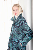 Young blond woman in transitional coat with leaf jacquard