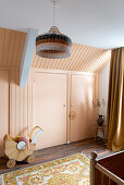 Girl's room with pink painted fitted wardrobes and old doll's pram
