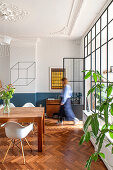 Wooden table with classic chairs in the dining room of an old building with herringbone parquet flooring and large window