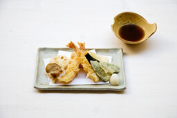 Tempura von Garnelen, Zuckerschoten, Pilz und Lotuswurzel, dazu Sojasauce (Japan)