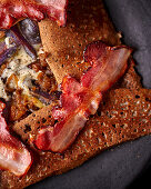 Galette with raclette cheese, red onions and crispy bacon