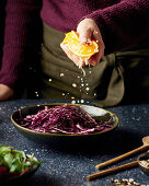 Squeezing orange juice over red cabbage for raw vegetable salad