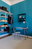 Vintage writing desk and open wardrobe in room with blue walls