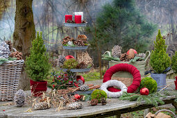 Weihnachtliche Etagere mit Kerzen, Zapfen, Christbaumkugeln, Moos, Zuckerhut-Fichte 'Conica' (Picea glauca) auf Gartentisch