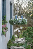 Adventskranz geschmückt mit Federn und Federkugeln auf der Terrasse aufgehängt