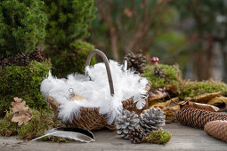 Weihnachtsdeko mit Christbaumkugeln, Federn und Zapfen auf Gartentisch