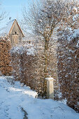 Verschneiter winterlicher Garten mit Rankbogen und Vogelhaus