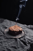 Schokoladenkuchen mit Schokoladen-Frosting und einer ausgepusteter Kerze
