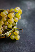 Green organic grapes in a bowl on a dark table
