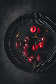 Frische rote Kirschen auf schwarzen Tellern