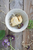 Bowl of snail-shaped cookies decorated with flowers of the alpine auricula (Primula auricula) and straw