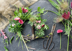 Kranz binden aus Küchenschelle (Pulsatilla), Vergissmeinnicht, Gänseblümchen (Bellis) und Birkenzweigen