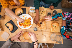 People from different cultures eating hamburgers with chips and snacks in a restaurant