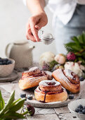 Blueberry cinnamon buns made from yeast dough with icing sugar