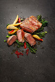 Beef steak wrapped in bacon with broccolini and pears
