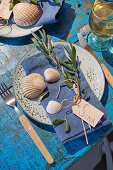 Griechisch gedeckter Tisch mit Olivenzweigen und Muscheln