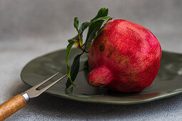 Ripe pomegranate with leaves on a plate