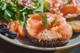 Person eating a salmon bagel sandwich