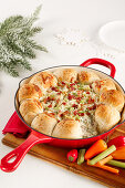 Bread roll wreath with warm artichoke and spring onion and bacon dip