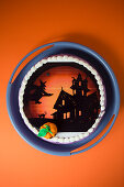 Orangefarbener Halloween-Kuchen mit Horrorschloss und Mini-Kürbis