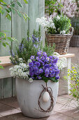 Ribbon flower (Iberis sempervirens) 'Candy', rosemary and primrose (Primula) 'Chrystal Fountai' in a plant pot on the patio with an Easter egg in a wreath