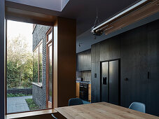 Open-plan kitchen with black cabinets, dining area and large window