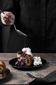 Sauce drizzling on plum cake with compote and cream