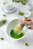 Frothing matcha with a bamboo whisk