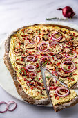 Linseed flour tarte flambée with red onions, mushrooms and bacon