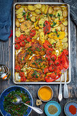 Chicken drumsticks with potatoes and tomatoes from the tray, served with gremolata
