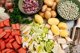 Zutaten für deftigen Erbseneintopf - Speck, Möhren, Porree, Kartoffeln, Zwiebeln, Majoran