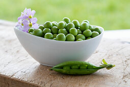 Bowl of fresh peas on a wooden table