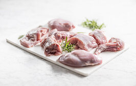 Portioned raw rabbit with rosemary on a chopping board