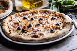 Pizza mit Speck, Zwiebeln und schwarzen Oliven