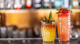 Mai-Tai-Cocktails in hawaiianischen Gläsern, garniert mit Ananas, Blaubeeren und Erdbeeren