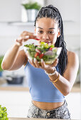 Young African American woman prepares healthy salad