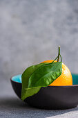 Orange with leaves in ceramic bowl