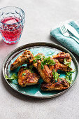 Roasted chicken wings with coriander and a glass of cherry cocktail