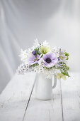Spring bouquet with anemones (Anemone coronaria) and hyacinths in a white vase