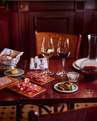 Table setting in the bistro with charcuterie platter, cornichons, red and white wine