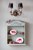 Wall shelf in shabby chic style with decorative objects and vintage wall light