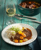 Braised beef with carrots and rice in a red wine sauce